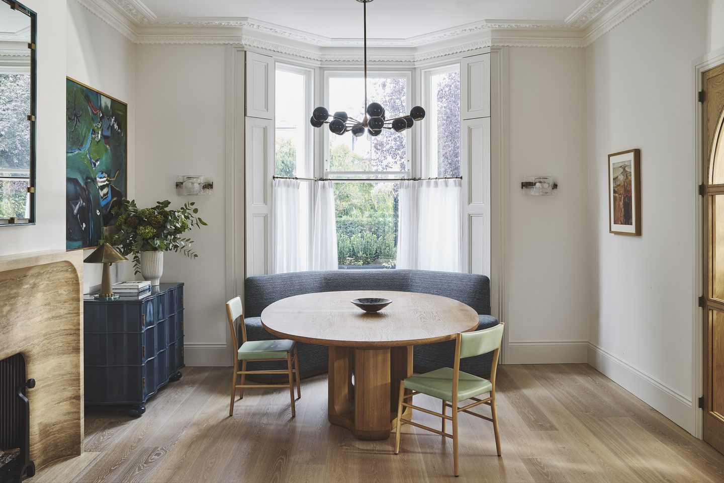 Dining area set into the bay window, with banquette seating and sculptural pendant