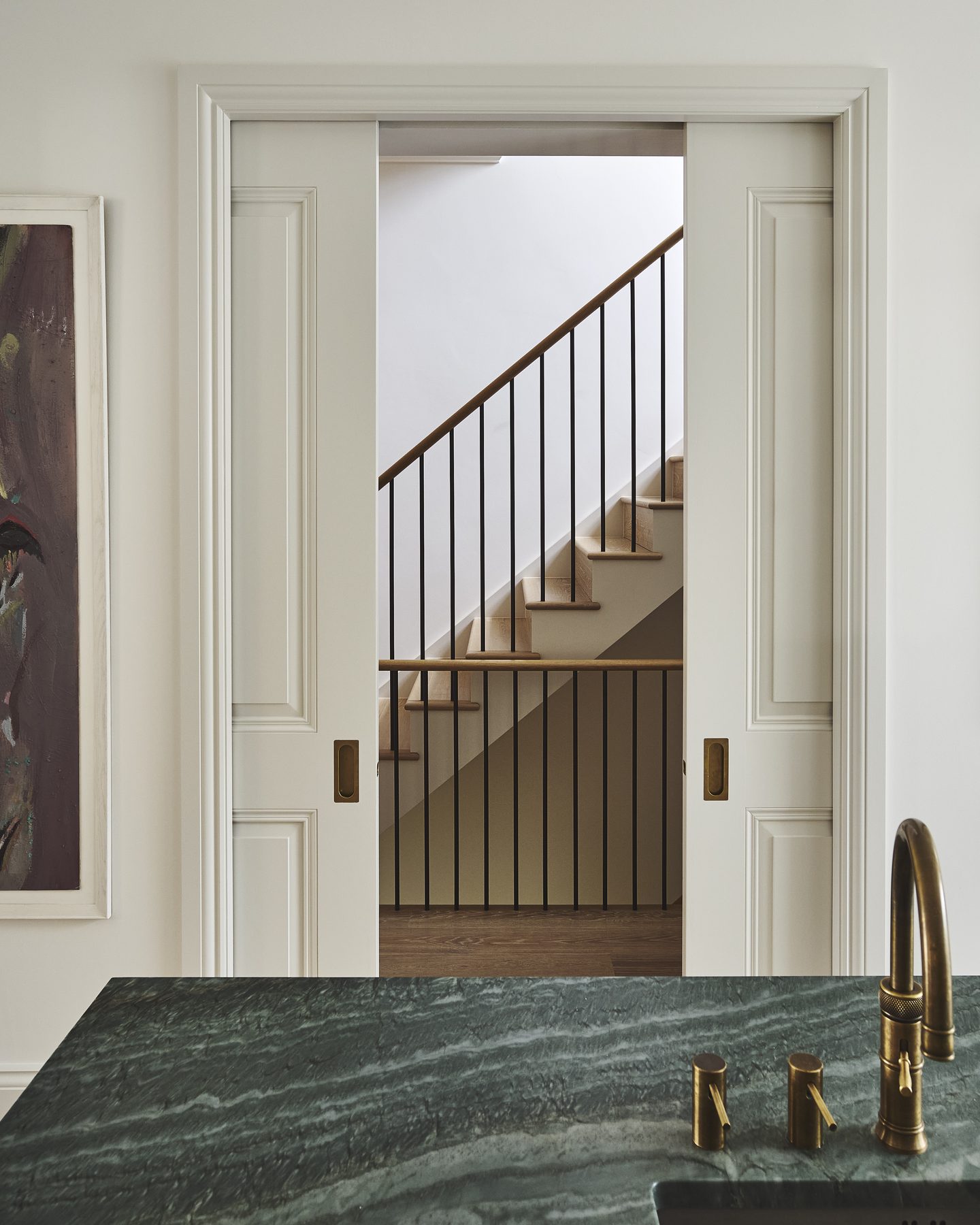 View from the kitchen through to the staircase, with green marble worktop and brass tap