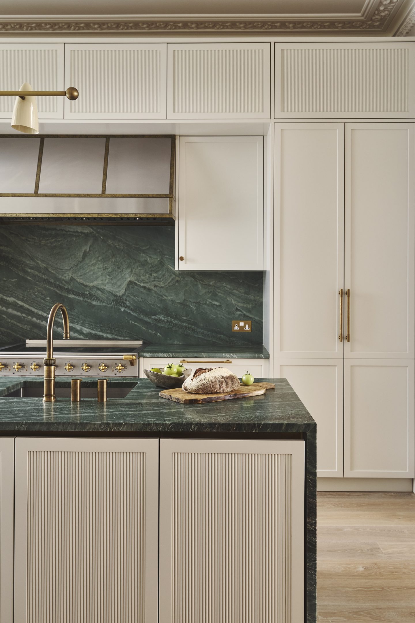 Kitchen detail with green marble splashback, brass tap and painted cabinetry