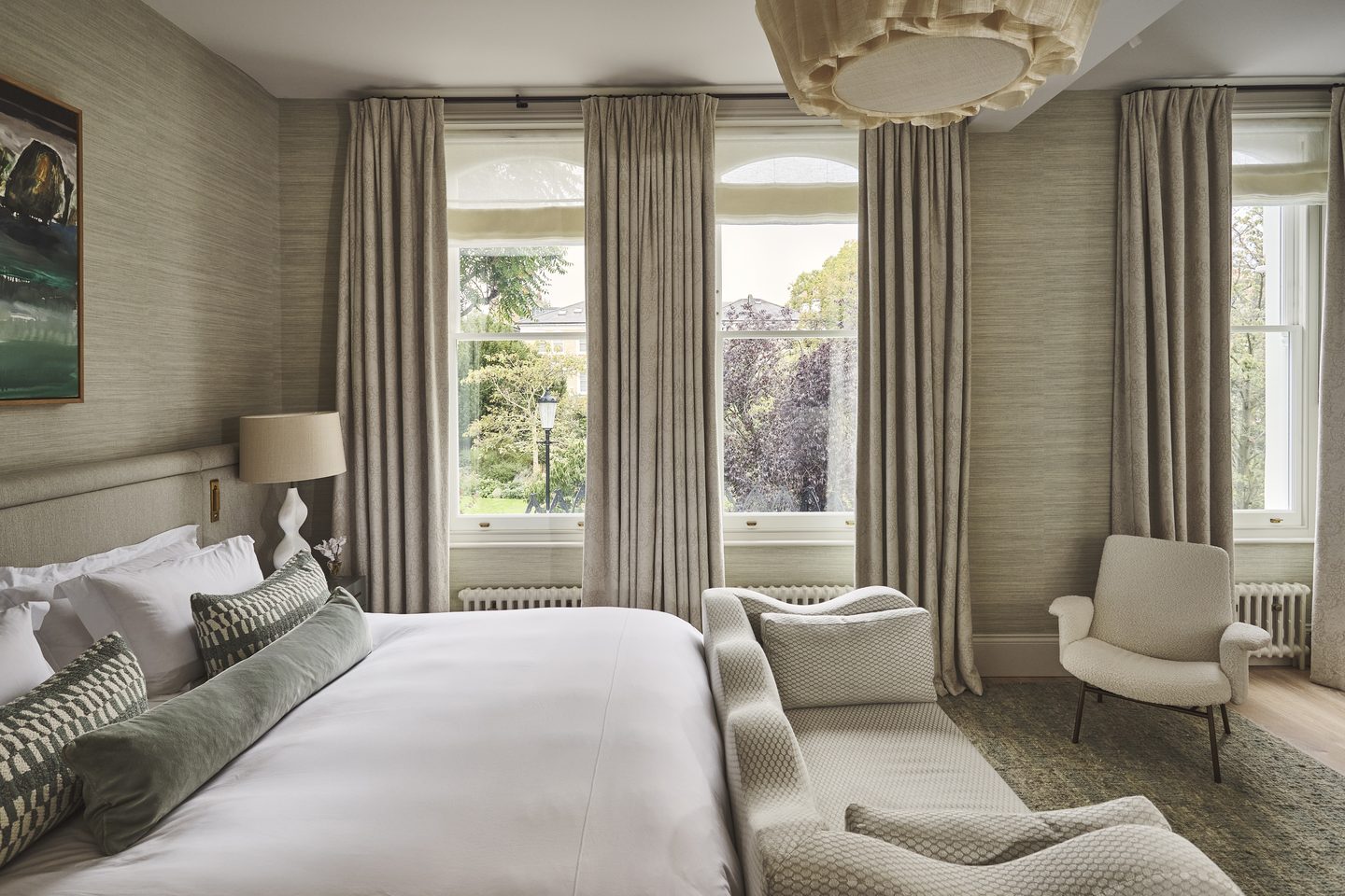 Principal bedroom with grasscloth walls and a pair of garden-facing windows