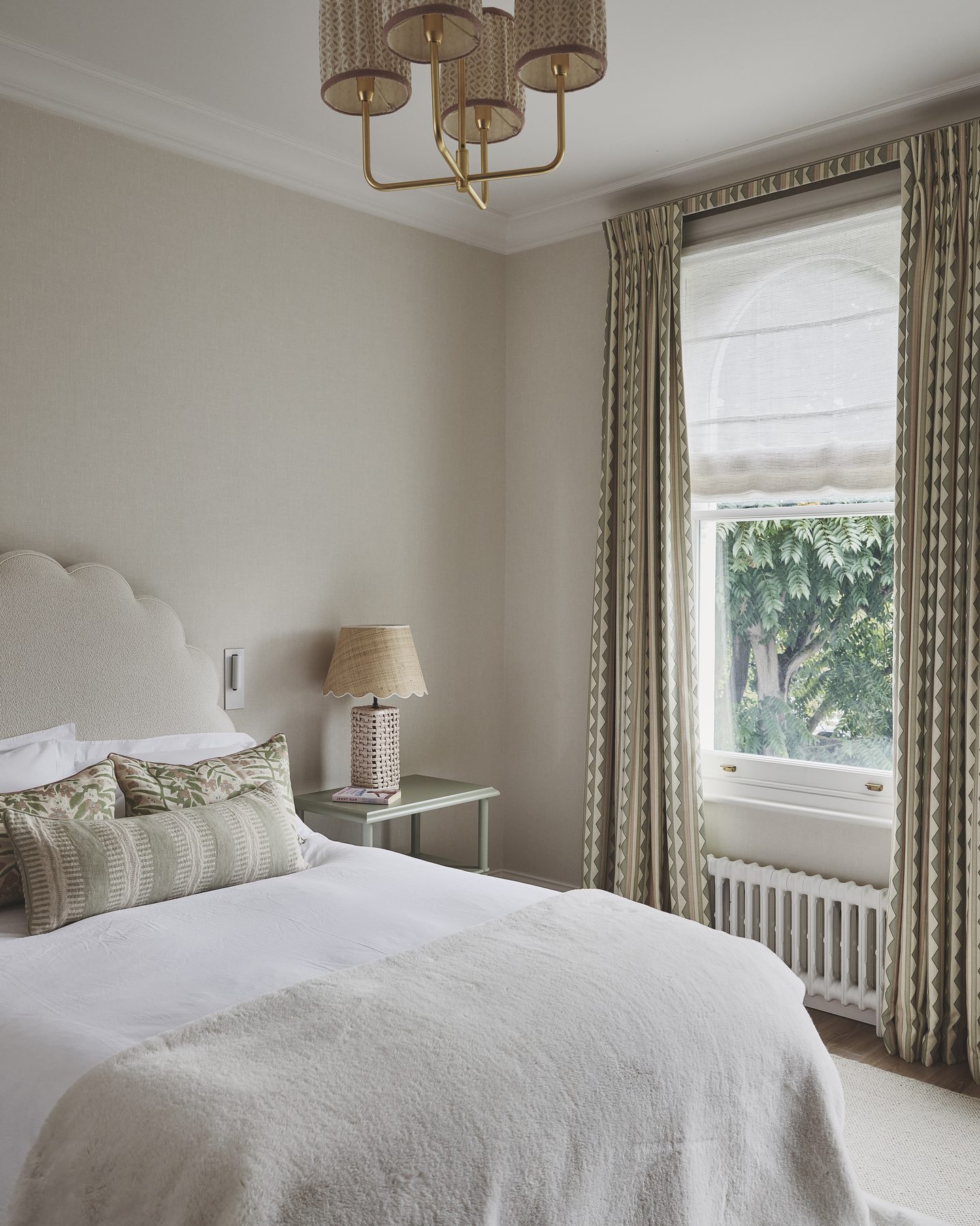 Bedroom with scalloped headboard and patterned curtains