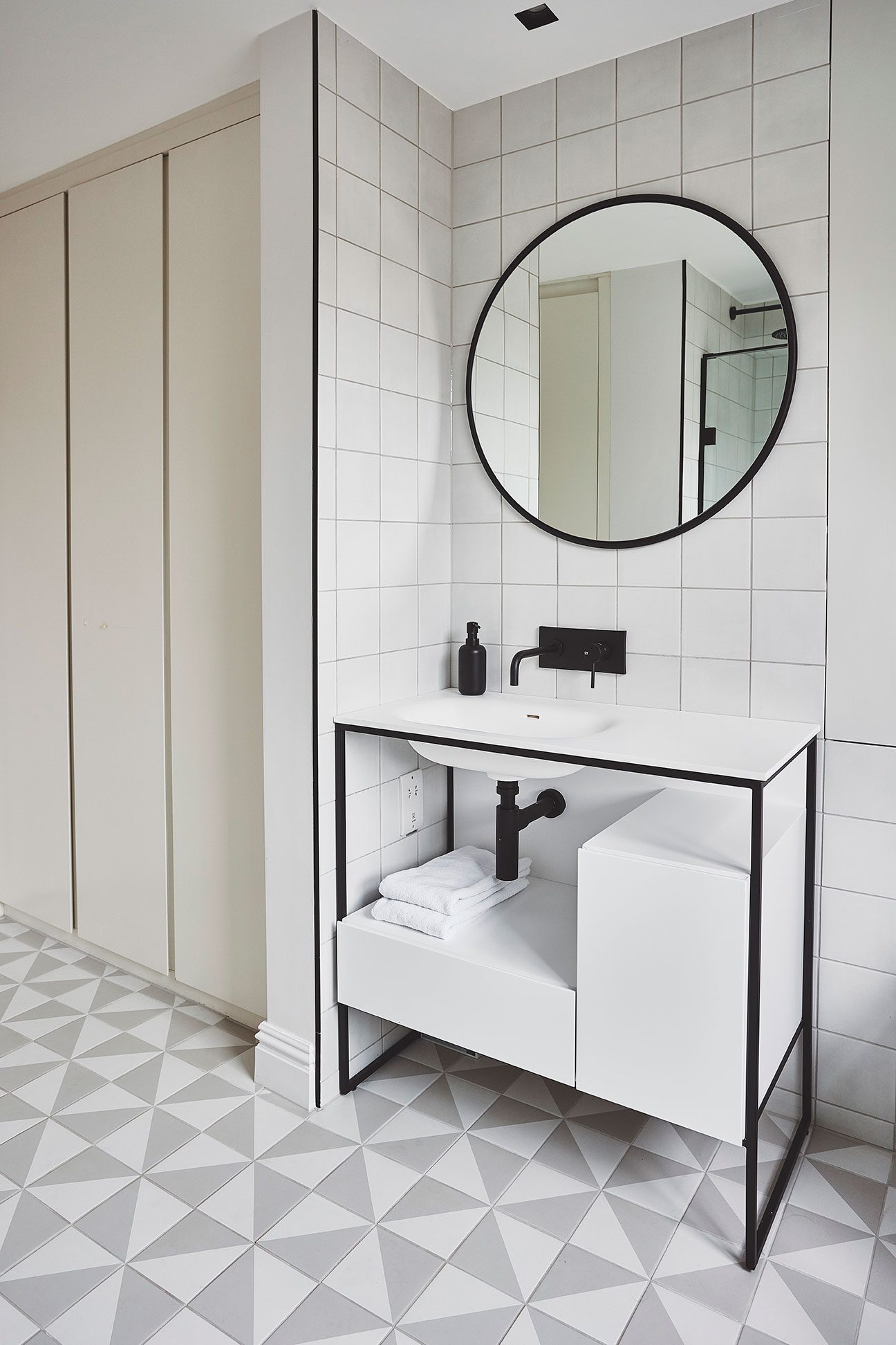 Cloakroom with round mirror and geometric floor tiles