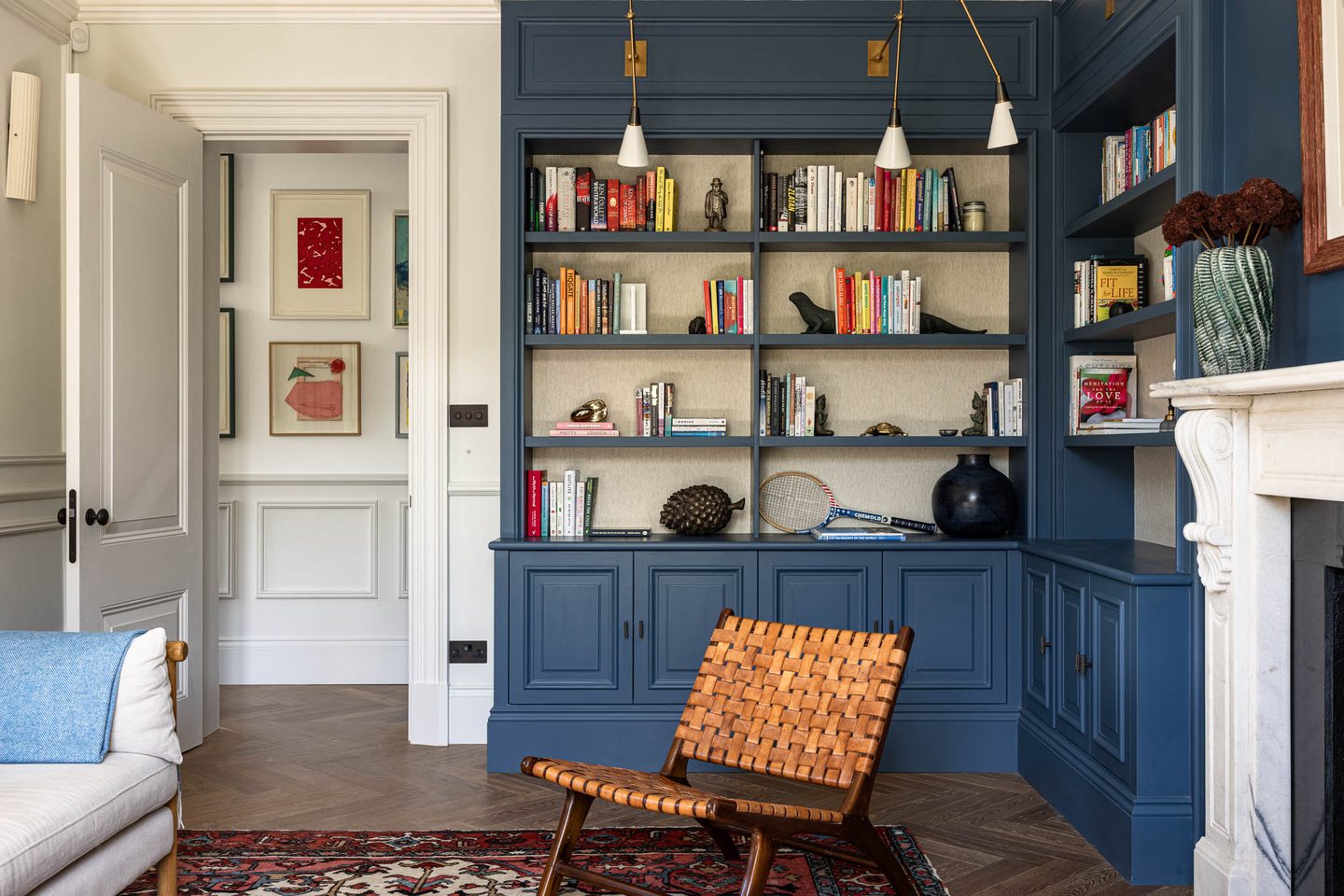Library with fitted blue joinery and woven leather chair
