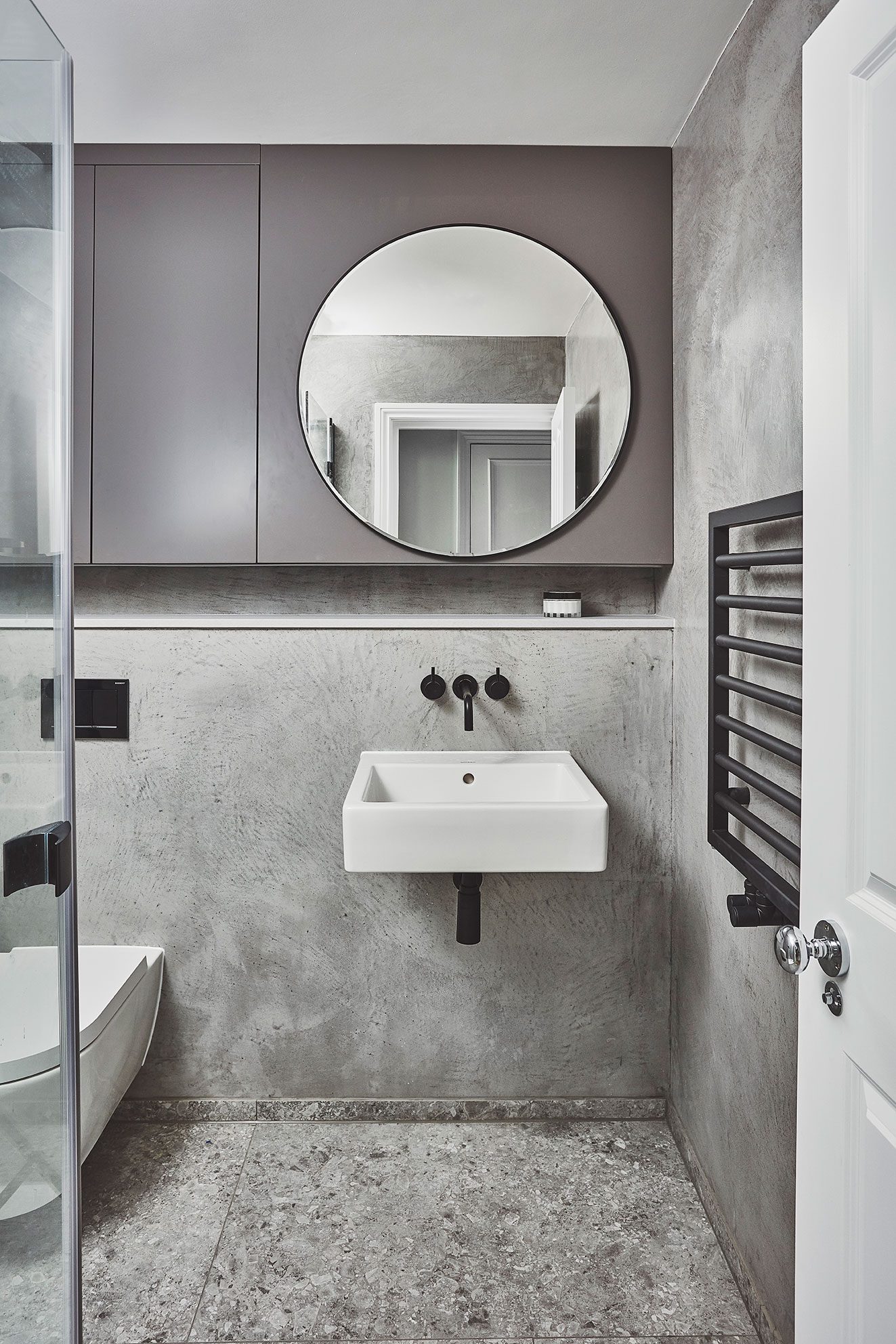 Bathroom with round mirror and wall-hung basin