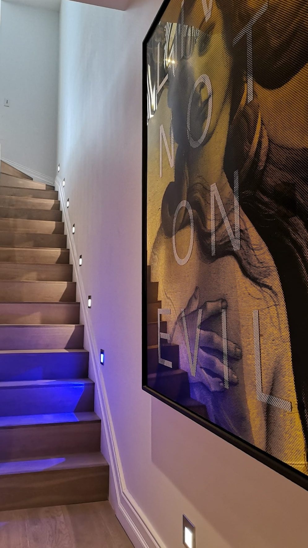 Staircase with lit treads and large-scale artwork