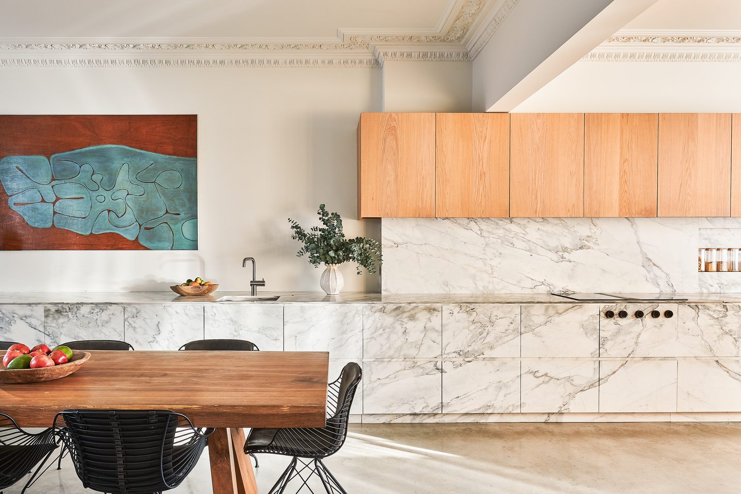 Kitchen with marble island and oak cabinetry, opening to the dining table