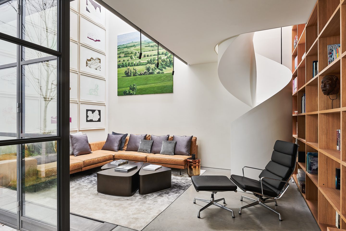 Double-height living space with spiral stair and fitted oak shelving
