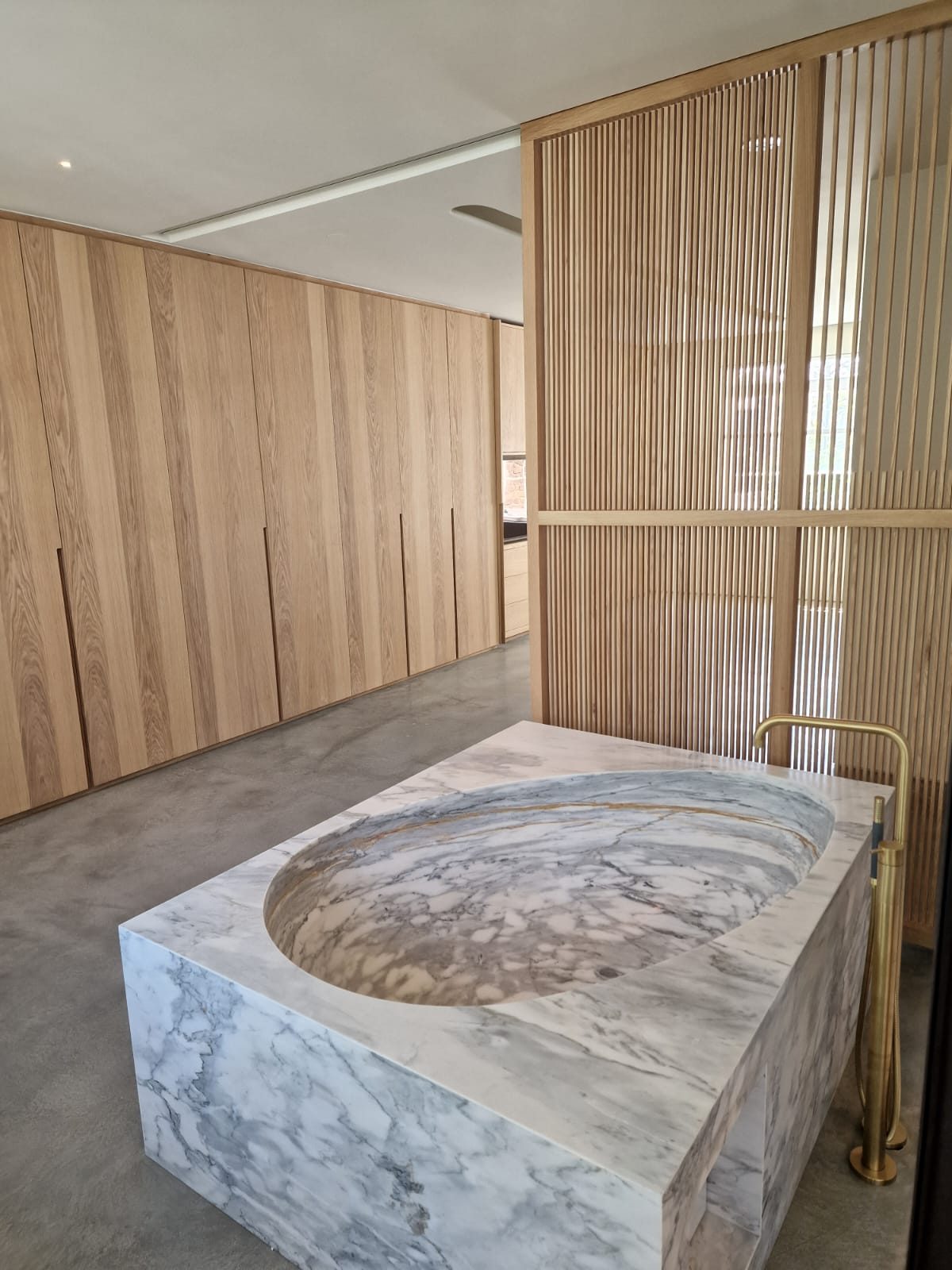 Sculpted marble bath set against fluted oak