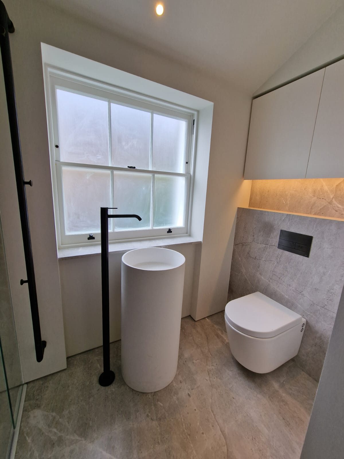 Cloakroom with freestanding basin beneath a sash window